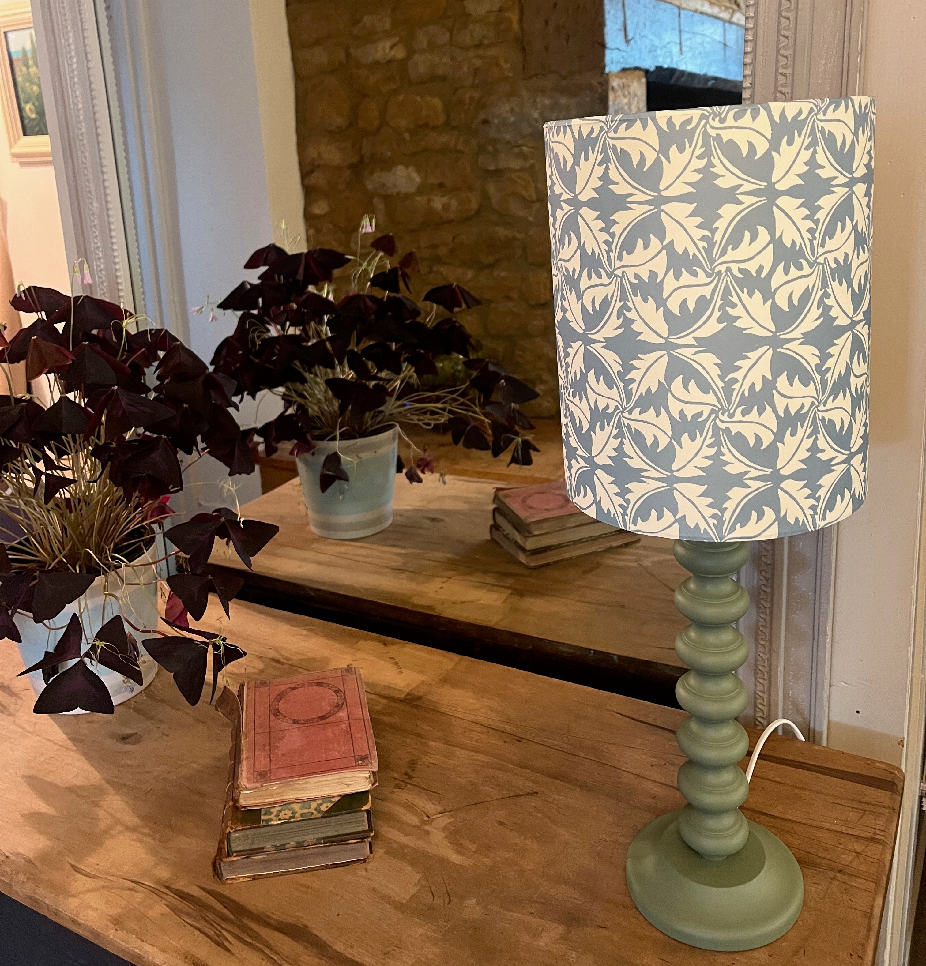 Contemporary handmade lampshade in blue and white with a modern design sitting on a hand painted green bobble base